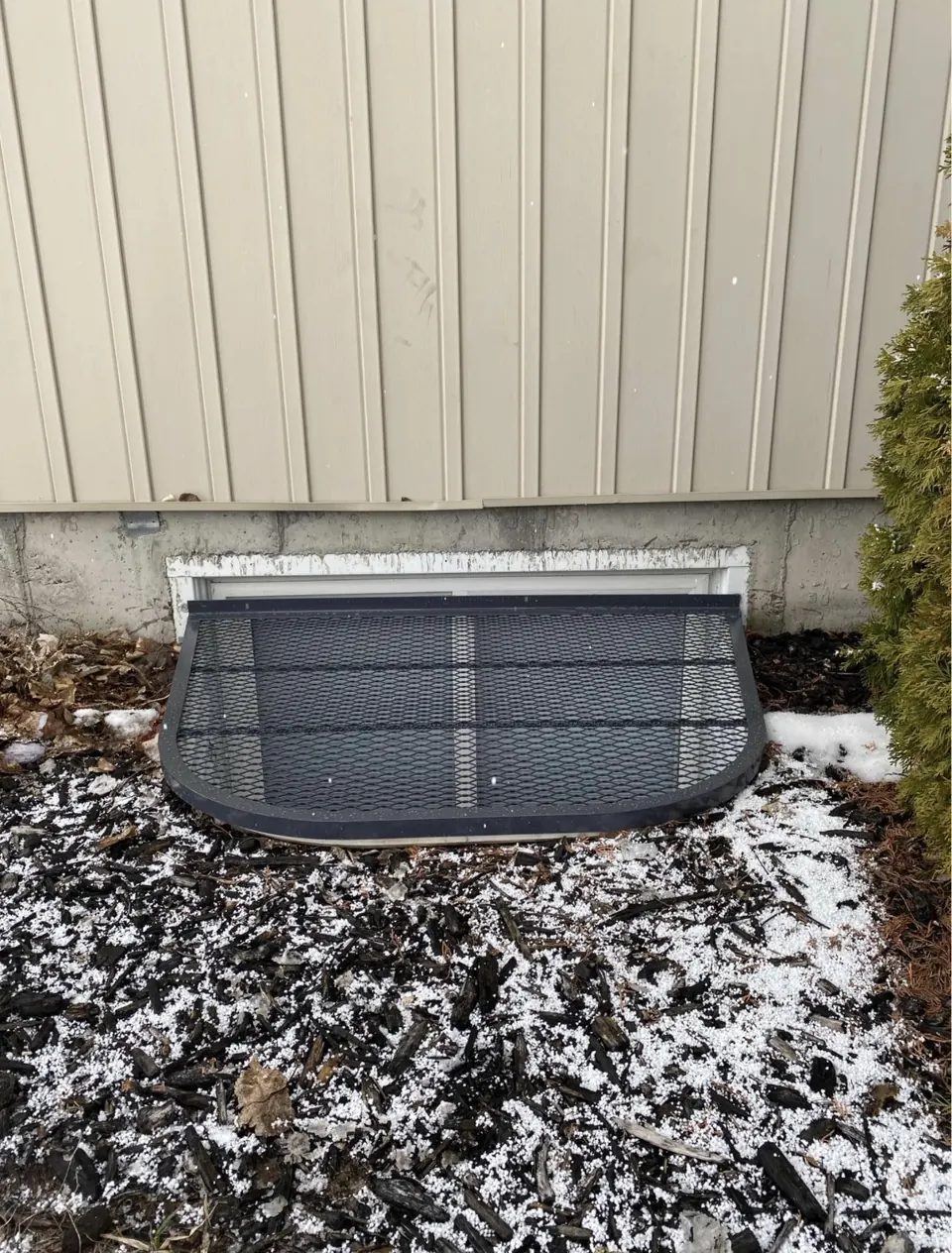 Completed black metal window well cover with a shaped frame and grid