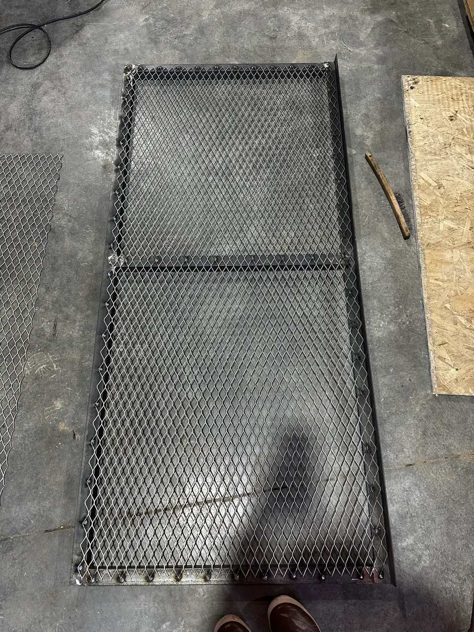 Expanded-metal window well cover with a welded frame before finishing